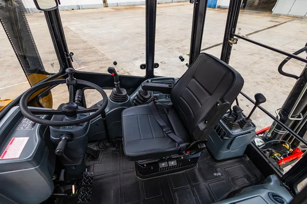 Interior da cabine da retroescavadeira DIEL DR608, com banco e comandos