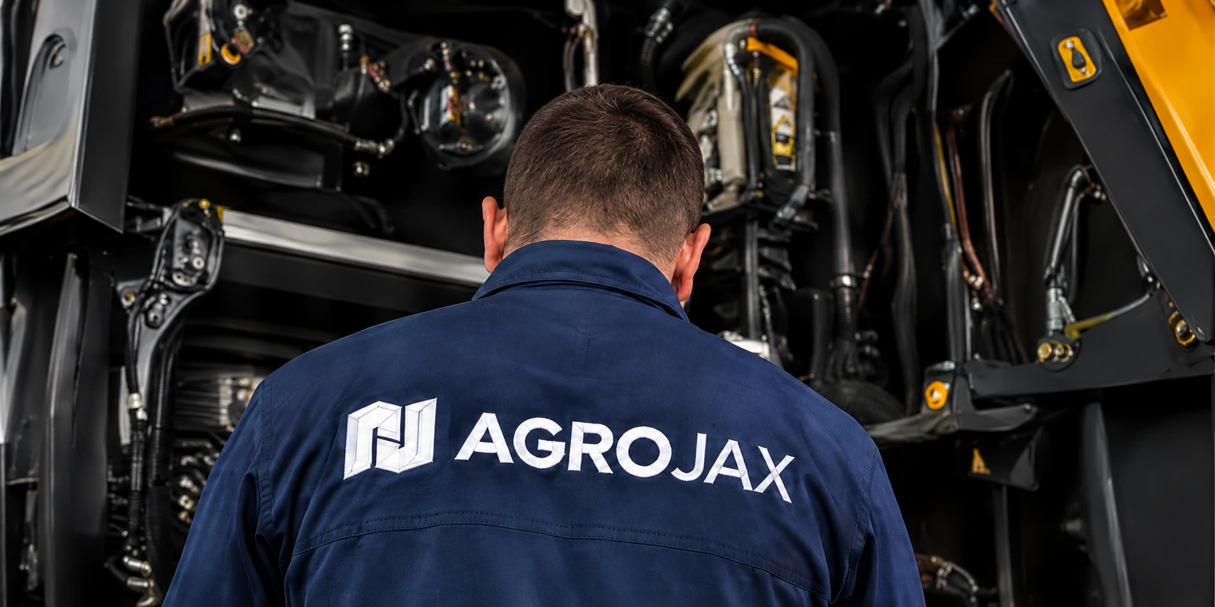 Técnico de costas com uniforme Agrojax, junto ao compartimento de um equipamento